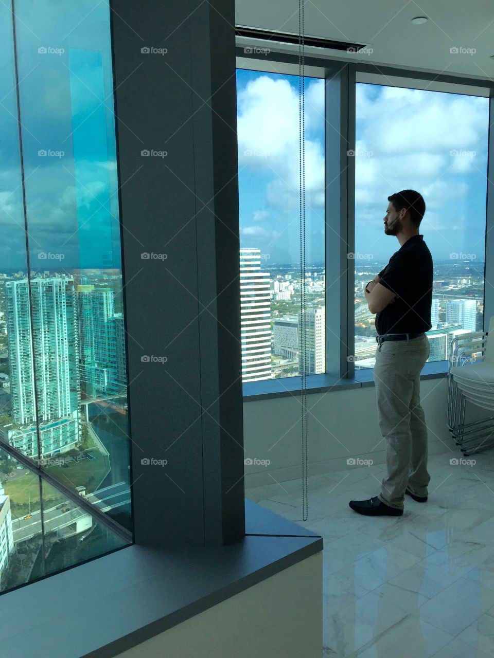 Contemplation. Young man standing by panoramic window in office