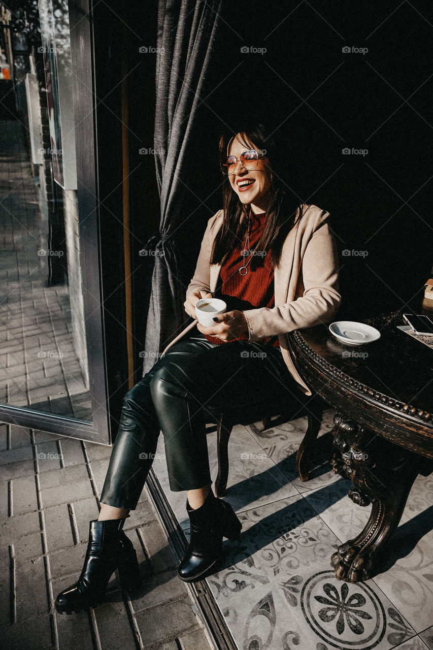 Beautiful brunette girl smile and take cup of coffee in street cafe