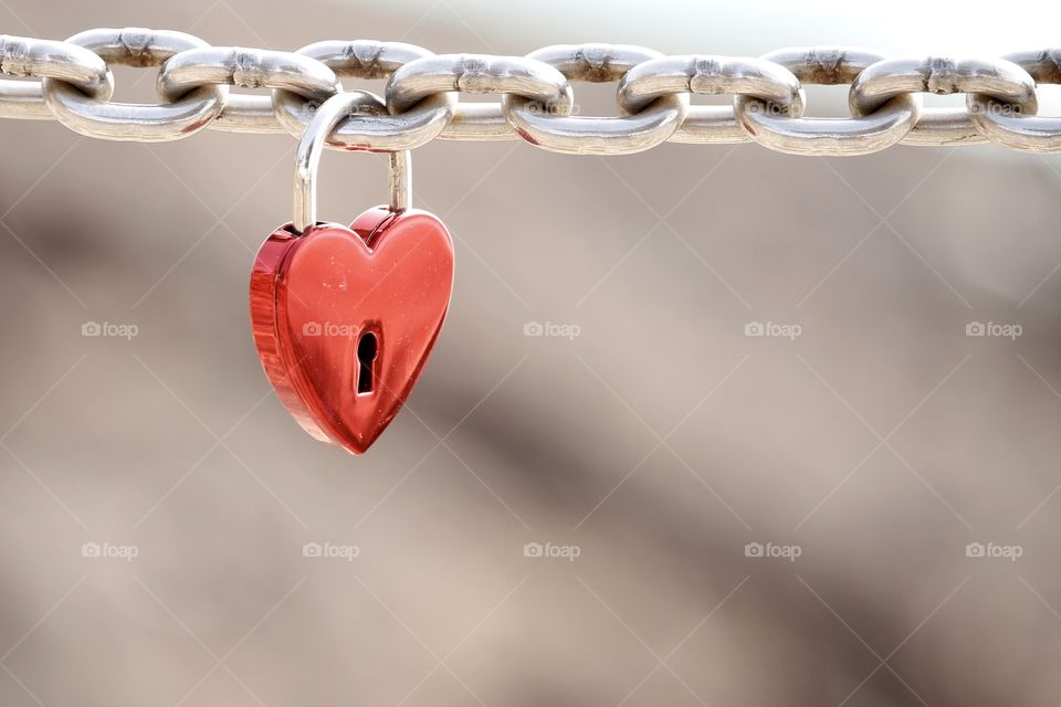 Love, red heart shaped padlock hanging on a metal chain - kärlek, rött lås format som ett hjärta hänger på en kedja av metall 