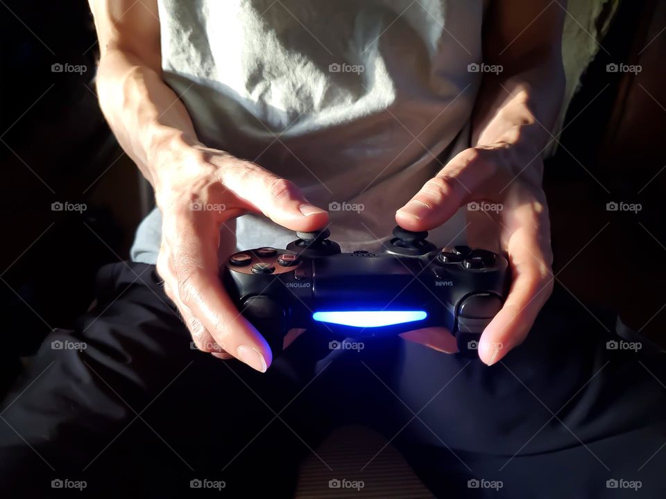 Closeup of a man holding a controller while playing video games.