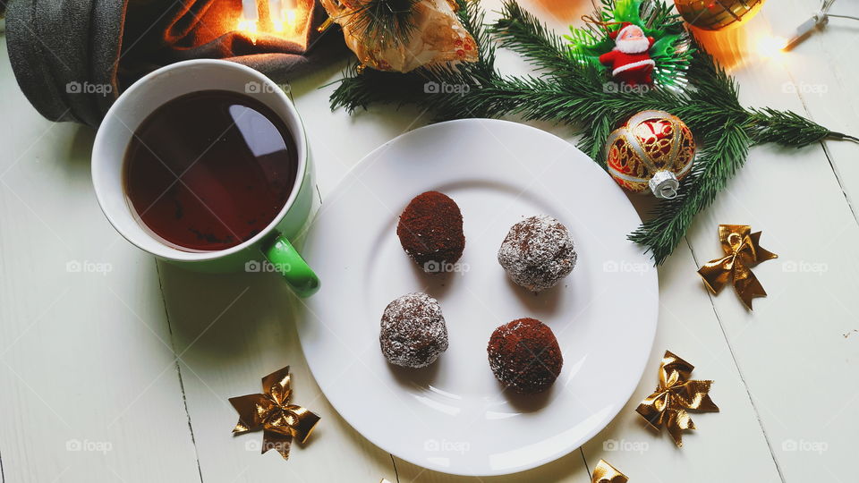 Christmas toys, a cup of hot tea, delicious Christmas garland cake on a white table