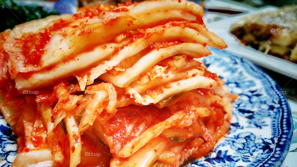 Korean kimchi, fermented cabbage in chilli paste layered as a stack and served on a plate.