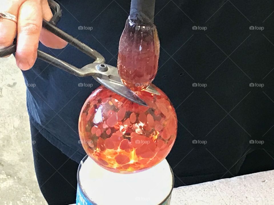 Person making orange glass ornament 