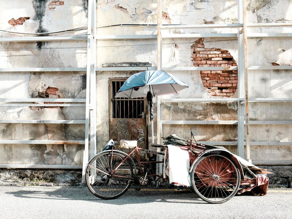 A Tricycle parked infront of an abandoned building in Penang, Malayai