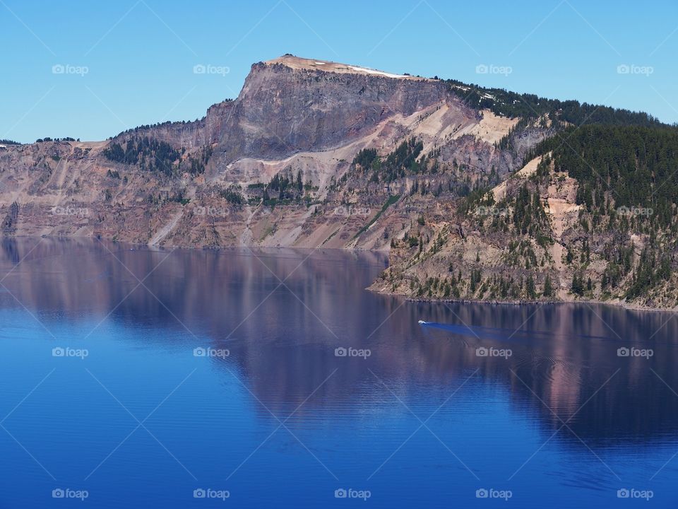 The rugged rim reflecting in the stunning Crater Lake on a beautiful summer morning in Southern Oregon. 