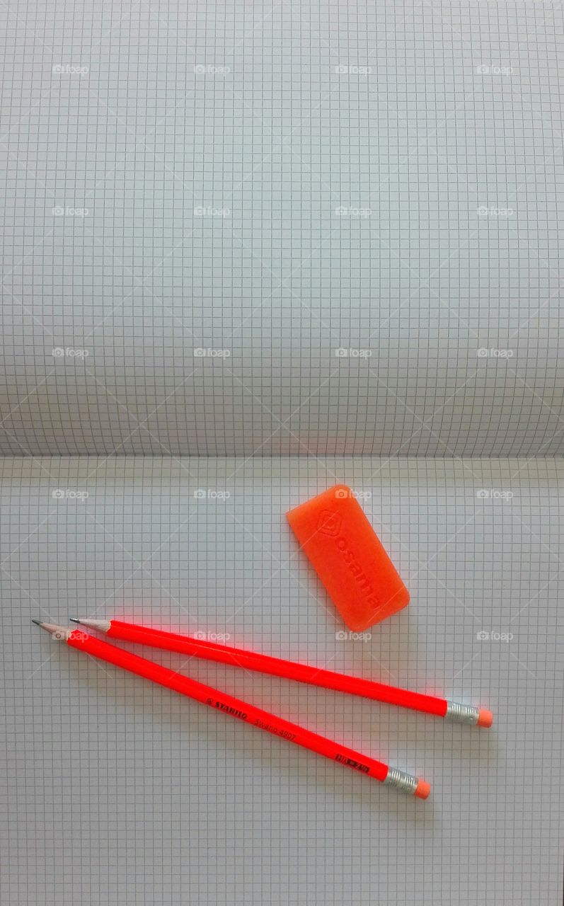 open check notebook with orange pencils and rubber