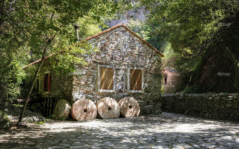 A stone country cottage under shady, leafy trees