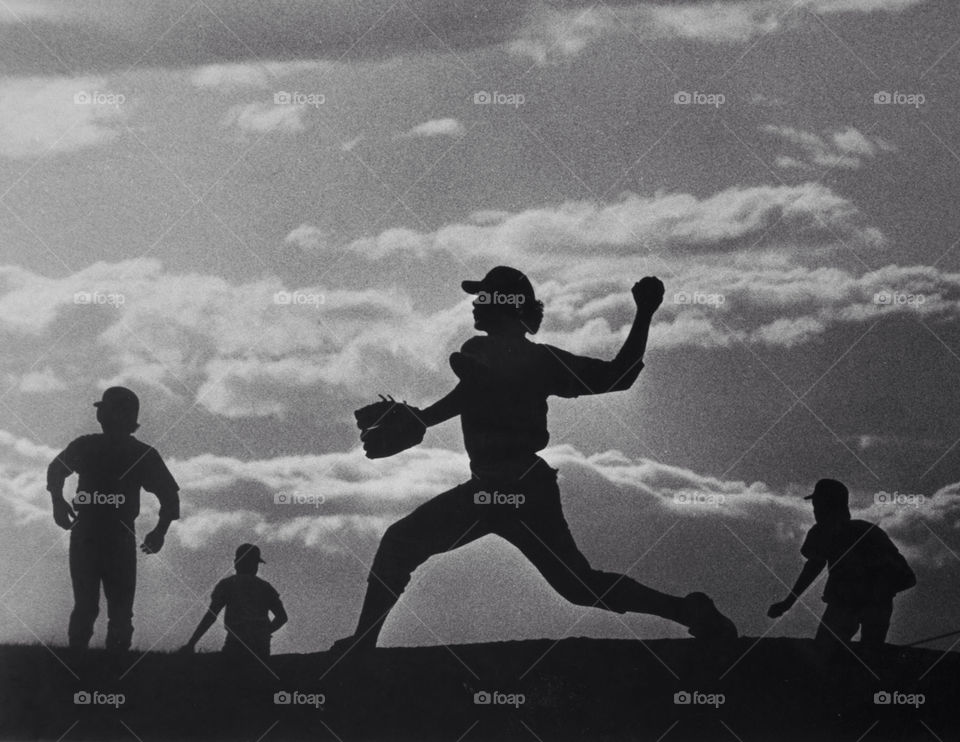 College baseball teammates are silhouetted against storm clouds during