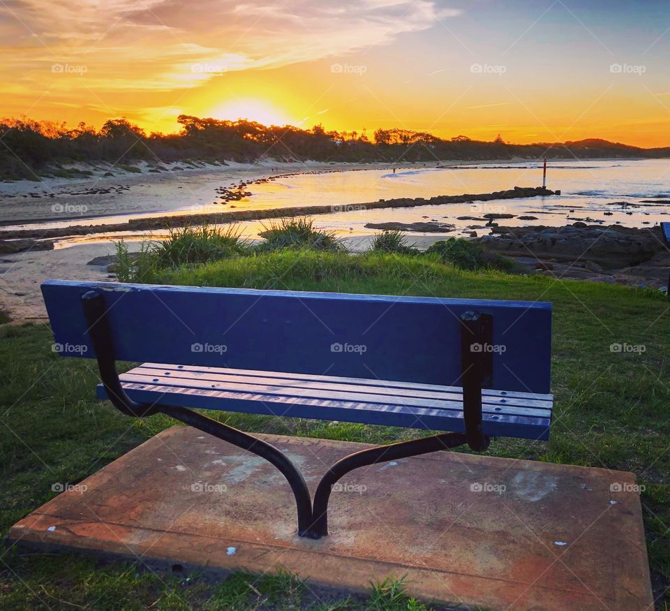 Blue bench at sunset at the beach 