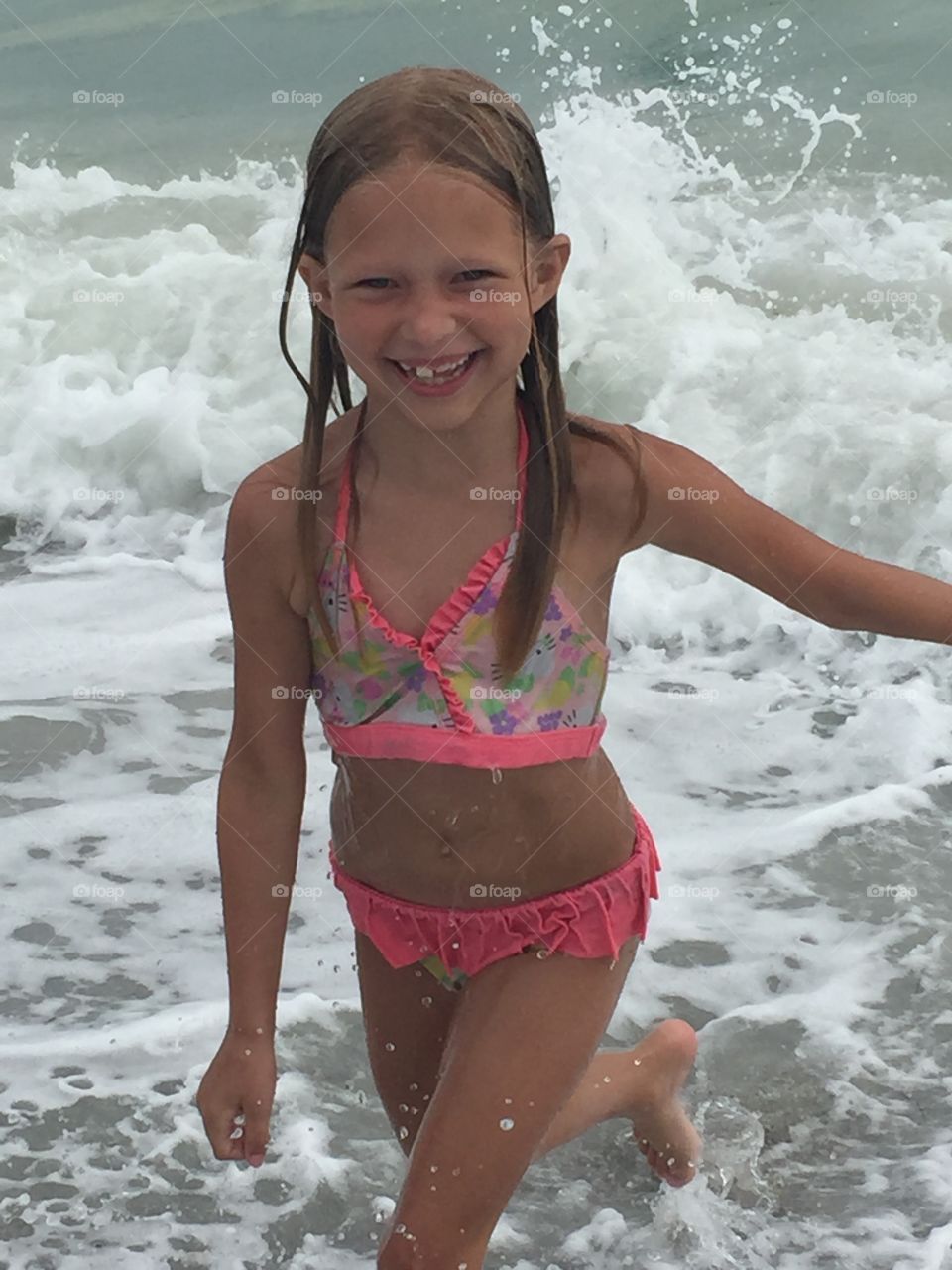 Little girl playing in the waves of the ocean