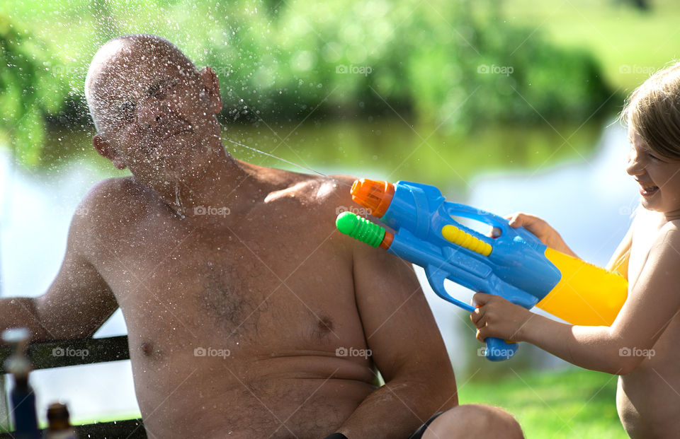 Girl and grandfather playing with water gun