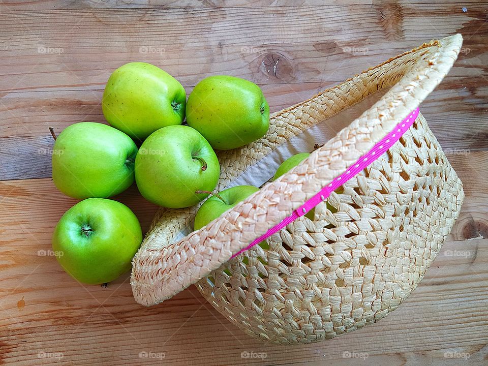 View from above.  Green apples and straw hat