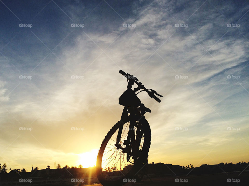 bycicle in front of sunset . bycicle silhouette in front of sunset 
