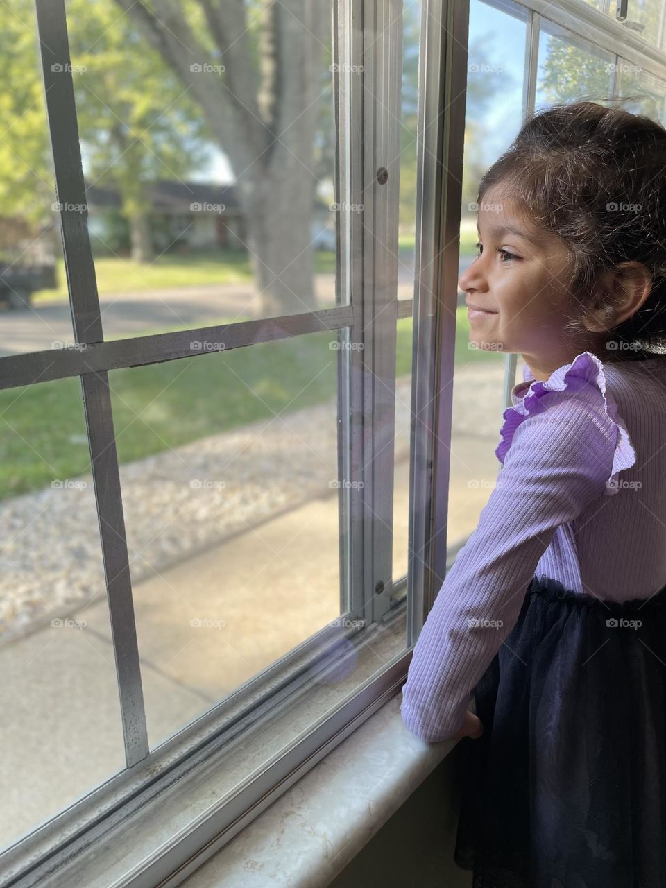 Curious little girl watches tree cutters take down tree, watching construction workers out the window, watching people work 