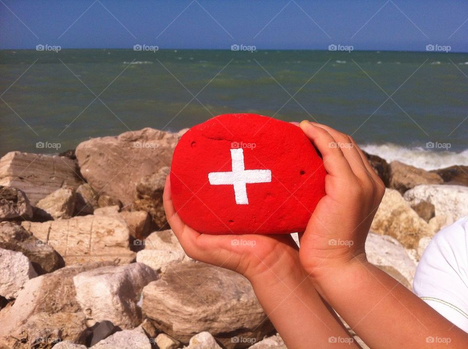 Switzerland's flag on a stone with coastal background