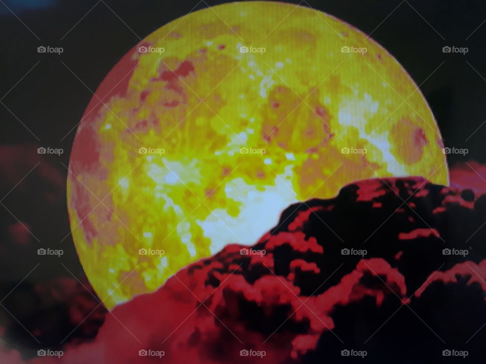 This photo shows the power of God the moon in a yellowish tone with the reddish clouds ahead.