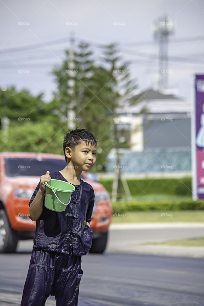 Asian boy holding Plastic bucket play Songkran festival or Thai new year in Thailand.