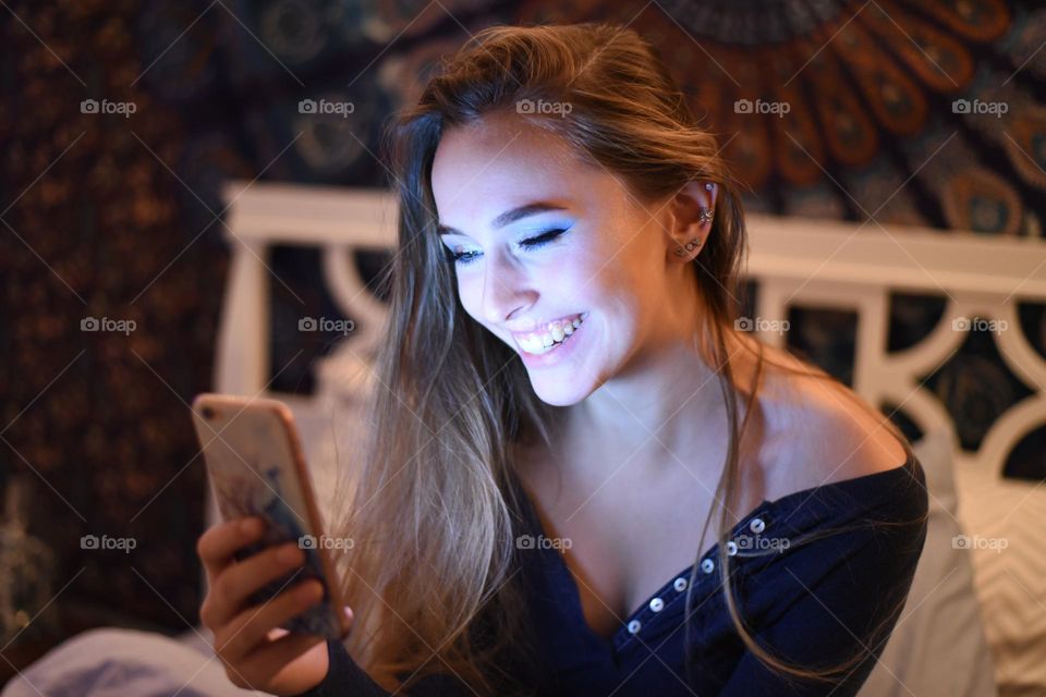 Young woman, smiling, recording herself on iPhone video