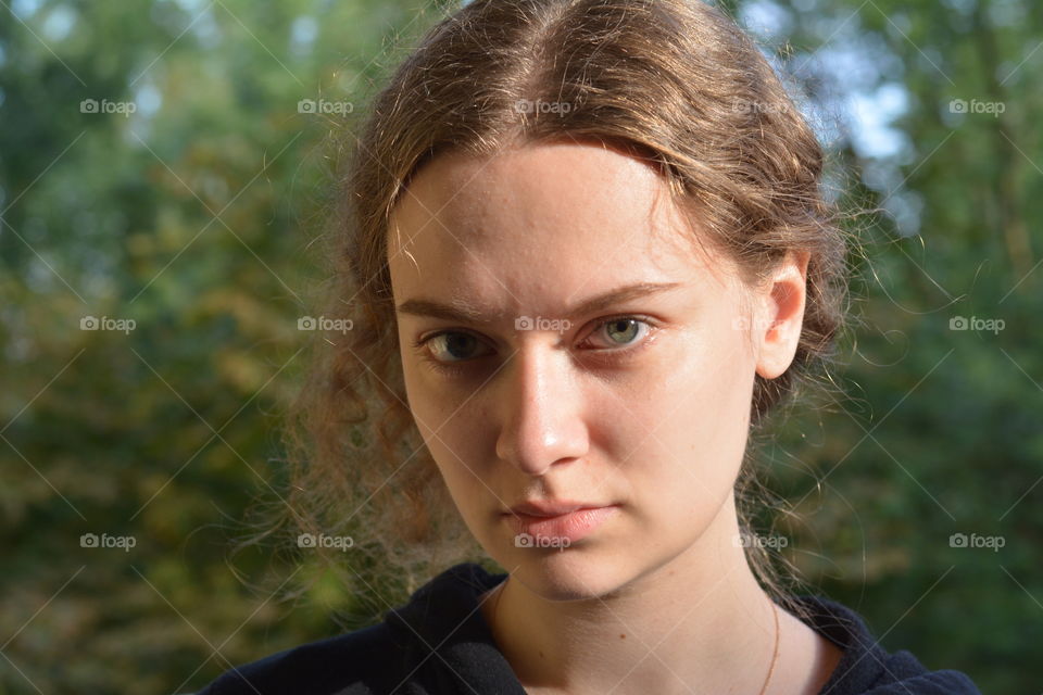 brunette girl beautiful portrait close up in sunlight outdoor green background