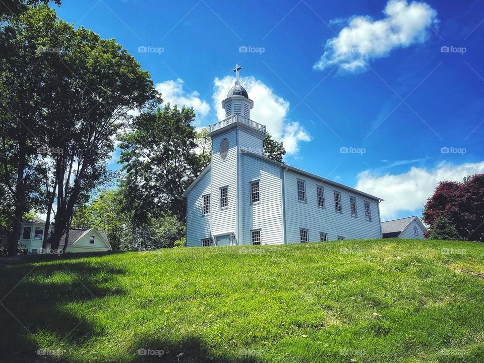 White church on a hill beneath blue sky and clouds 