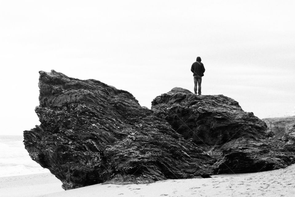 Man watching the ocean on a huge rock