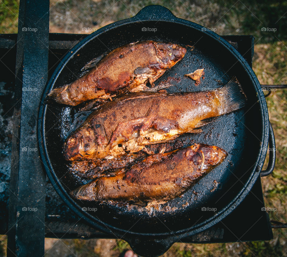 Fresh fish fried BBQ with a delicious crispy golden crust in a cast iron panels outdoor