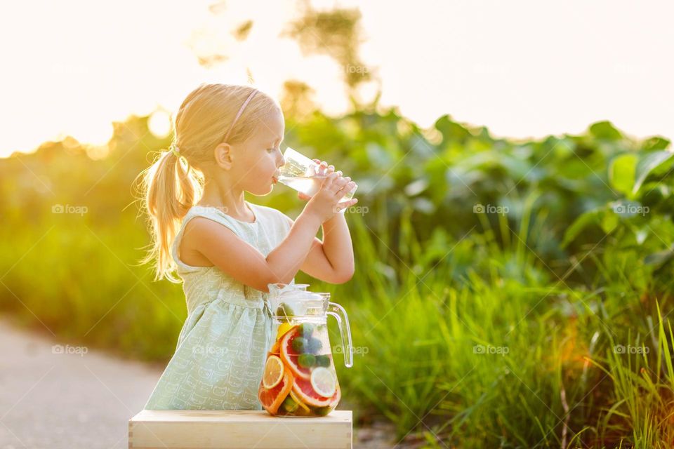 Happy kid drinking homemade lemonade outdoor 
