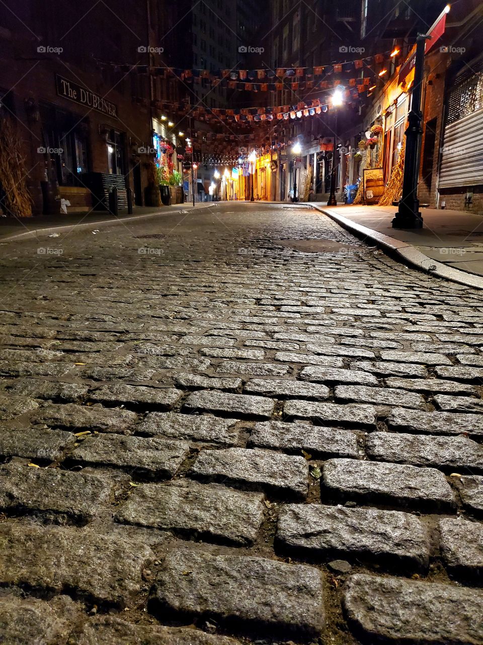 A brick road in Manhattan is dramatically lit