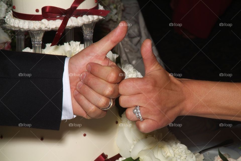 A newly wed couple give two thumbs up to a life journey together.