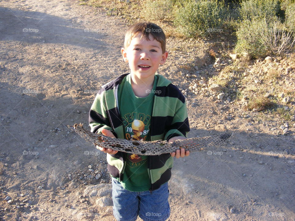 Boy holding a cactus skeleton in the desert.