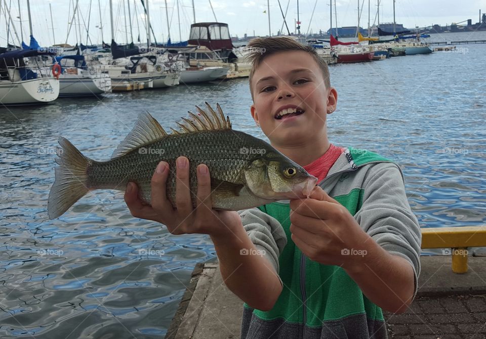 boy proudly showing fish he caught