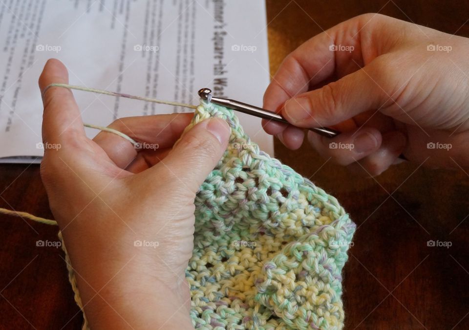 Woman's hands working on her craft with hook needle and yarn