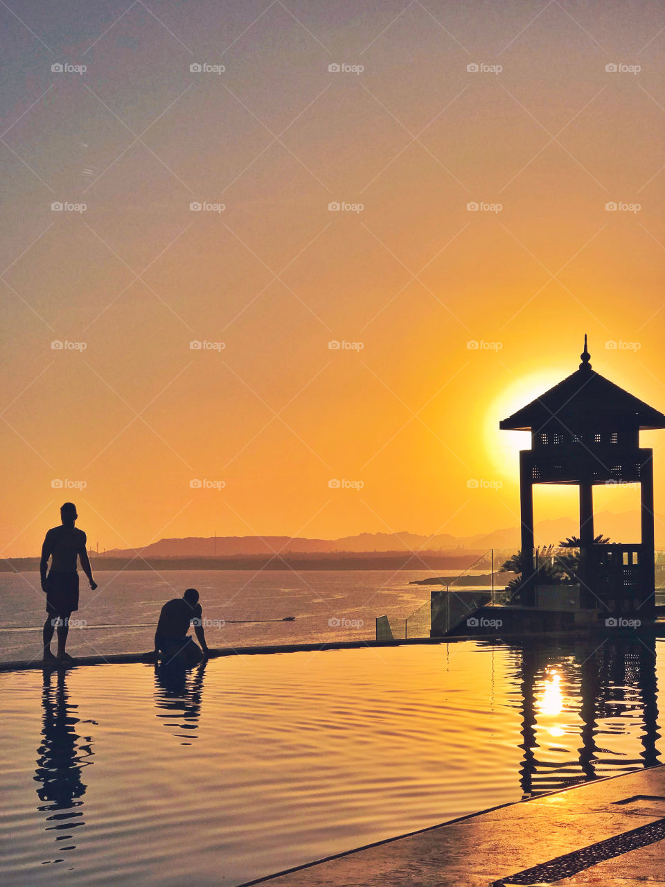 Two people near the swimming pool at the sunset