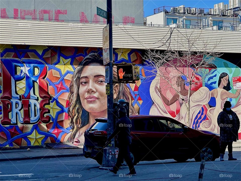 This colorful mural on „Jefferson St“ and „Broadway“ in „Bushwick“, Brooklyn spans almost an entire city block. A young hispanic woman next to the word „PRIDE“, a dancer and a mulatto woman are displayed in bright colors. 2024. Hypnotic Productions
