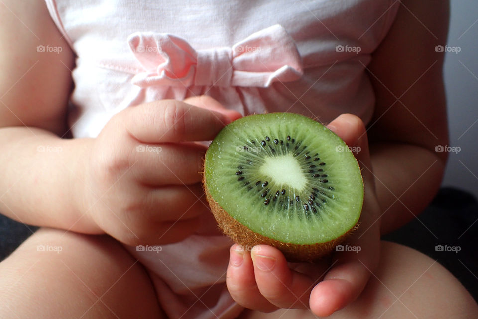 Baby holding kiwi