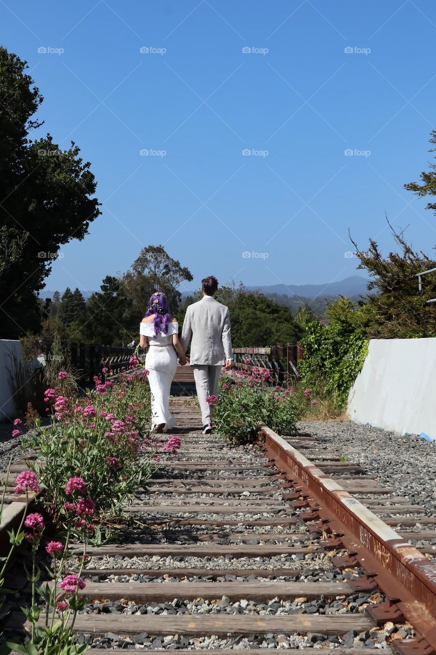 Happy bride and groom walking down the train tracks to start their adventure in life together 