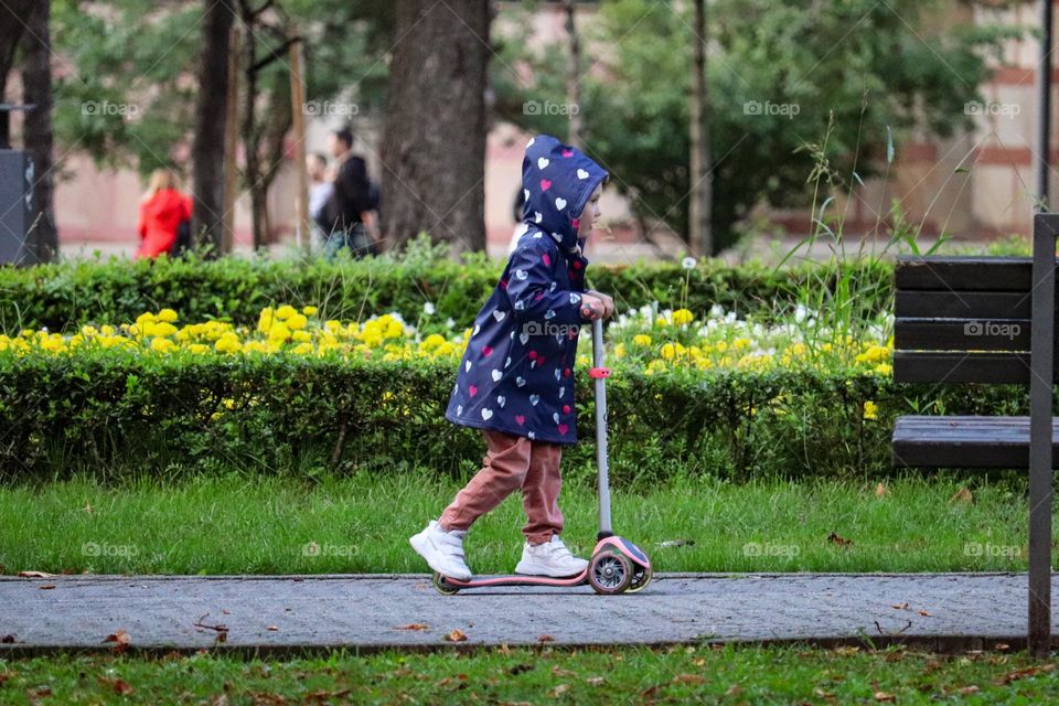 Autumn at the playground- Child riding a scooter