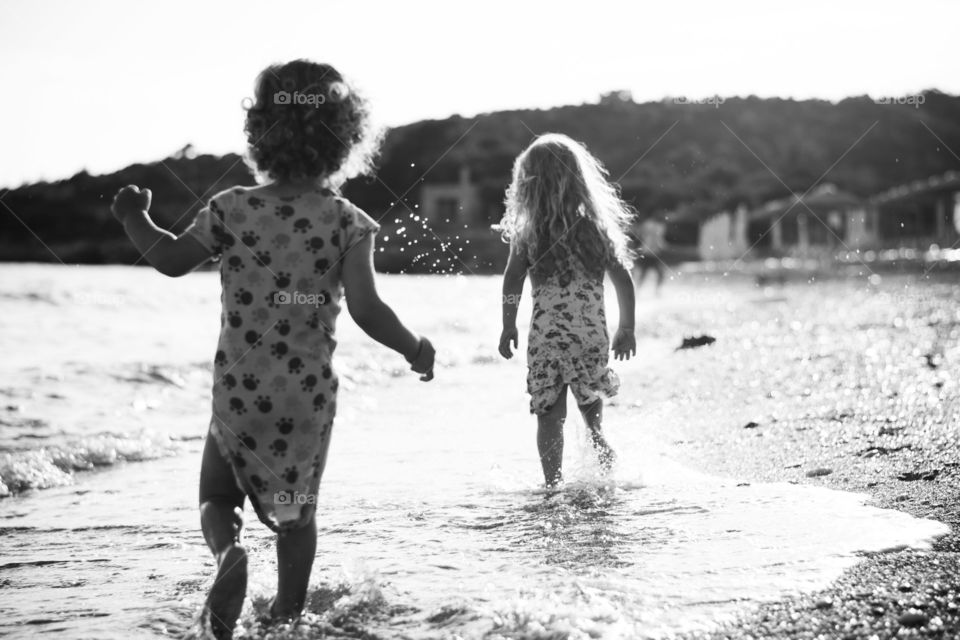 kids running at the beach. kids running at the beach accross the sea at sunset,monochrome effect.