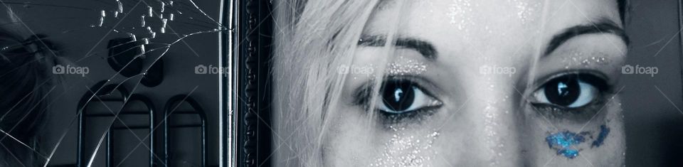 Cracked mirror and eyes with smashed glitter