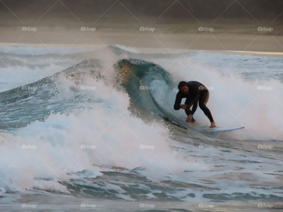 Summer time: Surfer riding a barrel wave at sunset on the Australian coast.