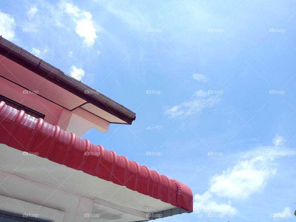 Low angle veiw of building against blue sky. Red roof with sunny day.