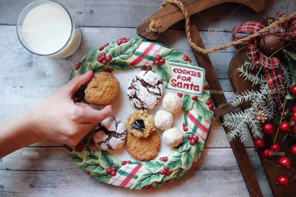 Child preparing cookies and milk for Santa