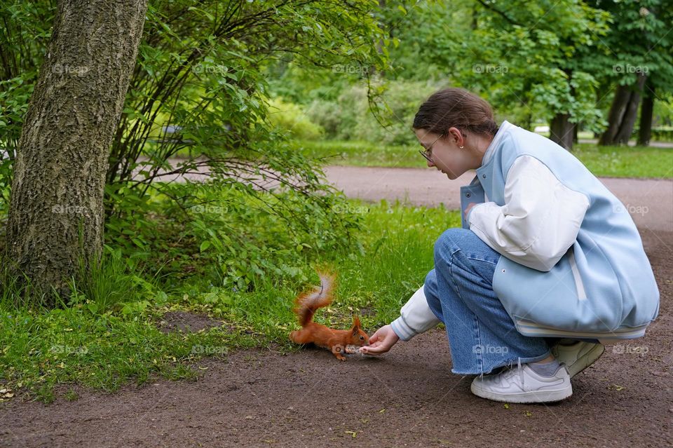 Girl feeding a squirrel in a city park