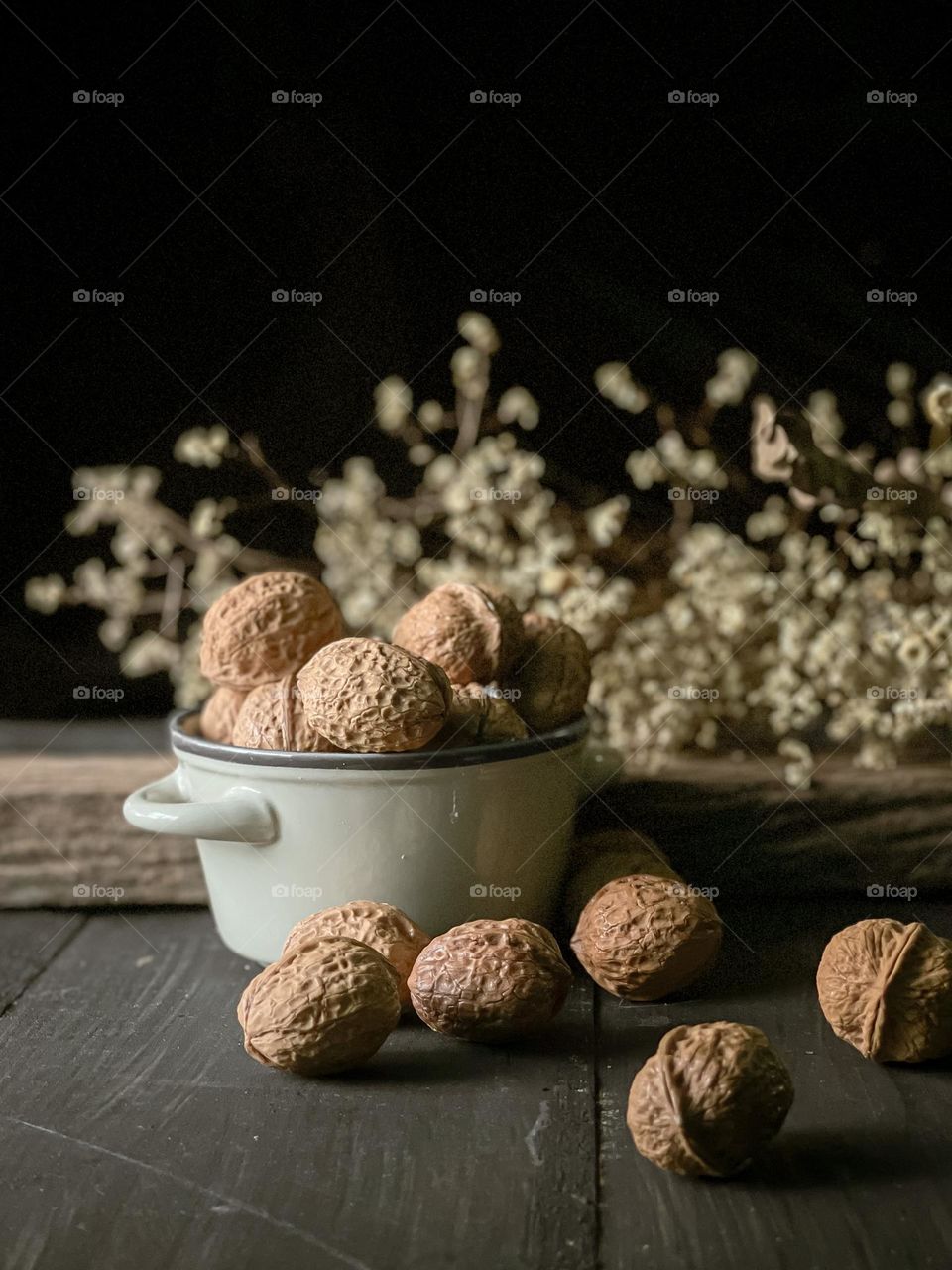 Walnut in a ceramic bowl and some scattered walnut on the wooden table.