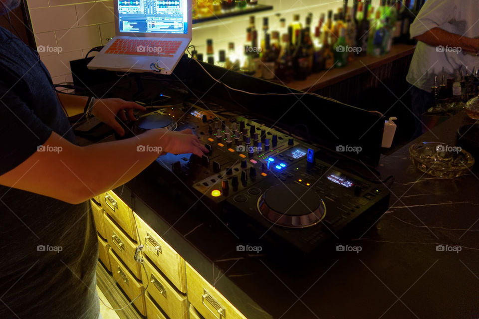 DJ mixing music at a bar club using a console and CD players. Dj mixing music using a laptop a usb and two professional cd players.