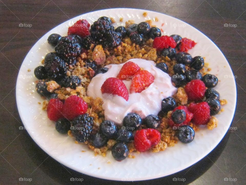 full plate of strawberries and yogurt raspberries blackberries and blueberries on granola