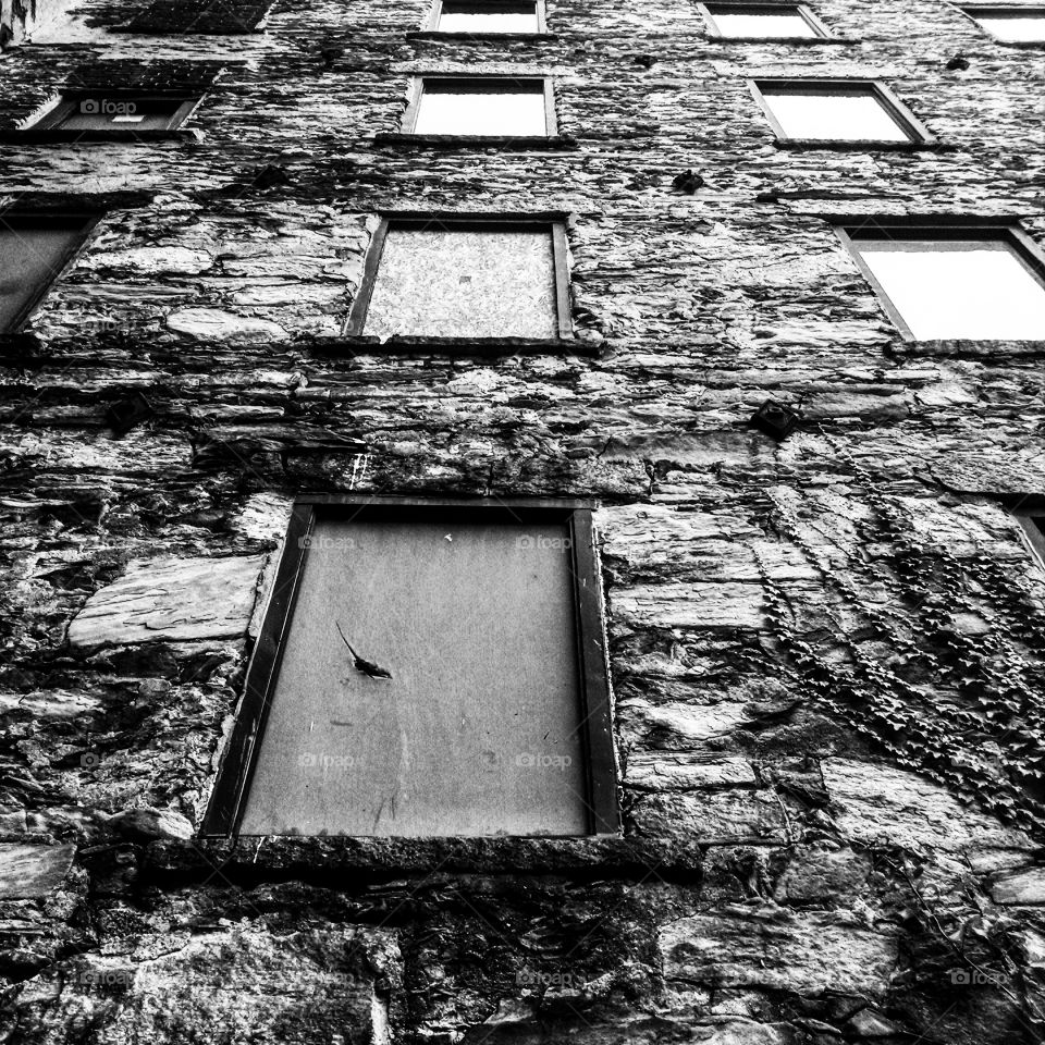 boarded up. looking up a stone building with boarded windows