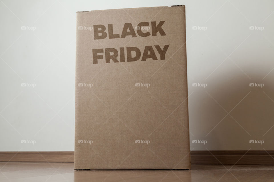 Cardboard box with black friday order written on the box placed on the floor in an empty room with a neutral background. delivery concept. economy concept. black friday concept. shopping concept.
