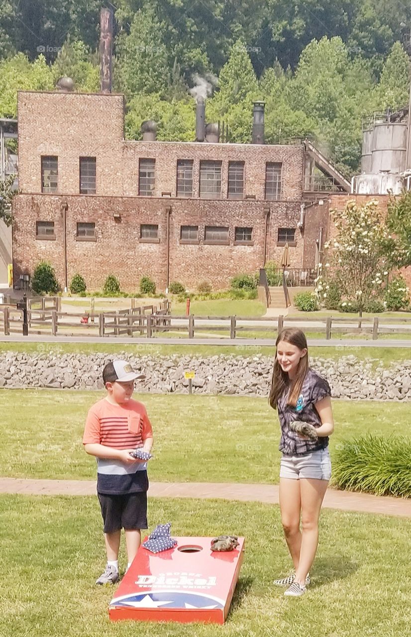 Fun filled days of summer for happy kids with smiles as they are enjoying corn hole in the lucius green grass yard of the George Dickel whiskey distillery at Cascade Hollows, TN.
