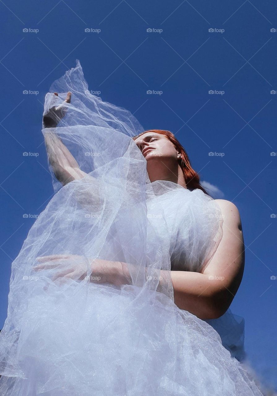 original photo of color contrasts, namely the clear blue sky and the white dress worn by the redheaded girl